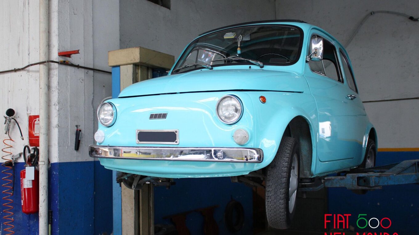 Fiat 500 d'epoca azzurra in officina durante la manutenzione delle ganasce dei freni a tamburo.